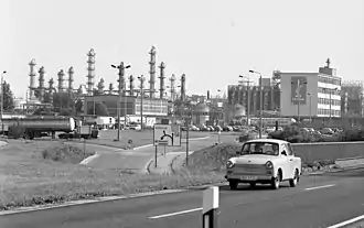 Photographie montrant une automobile en avant-plan, alors qu'à l'arrière apparaissent des installations industrielles.