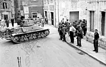 Des tanks circulant dans la rue d'une ville, sous le regard des passants.