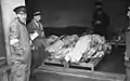 Point de collecte des cadavres où deux hommes juifs patientent devant des cadavres qu'un autre homme semble répertorier (25 mai 1941)