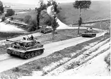 Photo montrant trois blindés allemands sur une route de campagne.