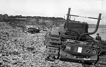 Photographie en noir et blanc d'un char d'assaut détruit sur une berge.