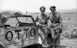 Deux pilotes en uniforme se tenant devant une automobile dont le côté porte l'inscription OTTO