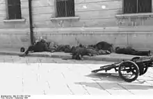 Image en noir et blanc d'un corps d'hommes en uniforme sur un trottoir et d'un canon d'artillerie