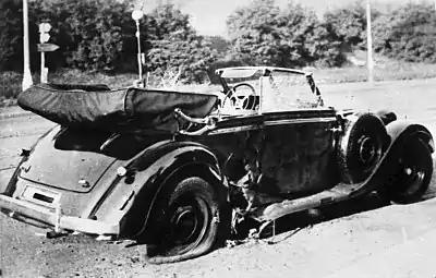 Photographie en noir et blanc de la Mercedes de Heydrich après l'assaut. Les dégâts dus à l'explosion de la bombe sont visibles à l'arrière du véhicule