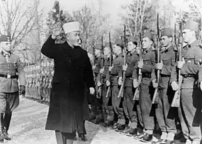 Novembre 1943 : al-Husseini saluant les volontaires musulmans bosniaques de la Waffen-SS avec un salut nazi. À sa droite se trouve le général SS Karl-Gustav Sauberzweig.