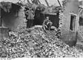 Deux soldats allemands posant devant une maison démolie.