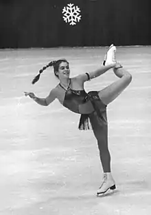 Photo en noir et blanc d'une patineuse se tenant la jambe gauche.