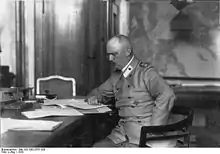 Photographie en noir et blanc d'un homme en uniforme militaire travaillant à un bureau