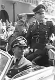 Photographie en noir et blanc de deux hommes dans une voiture, portant l'uniforme militaire de la Wehrmacht