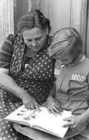 Photo en noir et blanc montrant une enfant et une femme lisant un livre