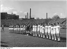 Photographie en noir et blanc de deux équipes de football alignées.