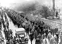 Photographie en noir et blanc dune colonne d'hommes juifs arrêtés à Baden-Baden à l'issue du pogrom