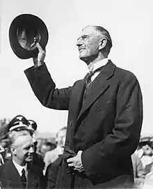 Photographie en noir et blanc de Neville Chamberlain, son chapeau à la main, à Munich le 29 septembre 1938