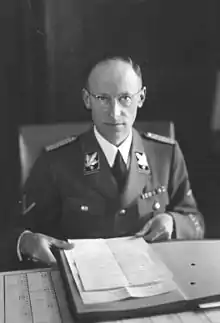 Photo en noir et blanc d'un homme en uniforme de SS assis à un bureau
