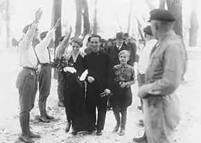 photographie en noir et blanc montrant Magda et joseph Goebbels avançant entre deux rangées de membres de la SA en chemises blanches