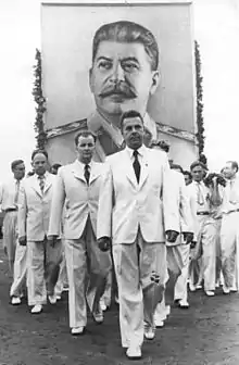 Photo noir et blanc d'hommes en costume blanc portant un portrait de Staline.