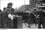 Est : agente de la police de circulation (« souris blanche ») devant des bâtiments en ruines, mai 1949.