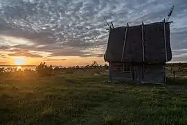 Au soleil couchant, la silhouette d'un petit bâtiment, presque une cabane ; on aperçoit la mer.