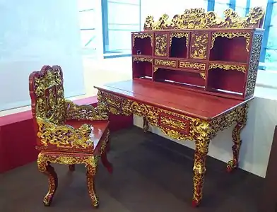 Bureau et son fauteuil en bois laqué rouge et aux nombreuses garnitures asiatiques dorées.