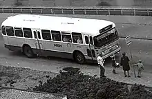 Photographie en noir et blanc d'un véhicule accueillant des passagers.