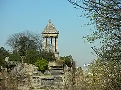 Photographie en couleurs d'un temple de gréco-romain entouré d'arbres, situé au niveau d'un belvédère, au sommet d'une falaise.