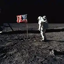Un astronaute regarde le drapeau américain.