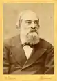 portrait photographique en noir et blanc en buste et de face d'un homme portant une barbe