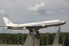 photographie en couleur d’un avion exposé à l’extérieur en étant posé sur trois haut plots en béton donnant l’impression qu’il décolle