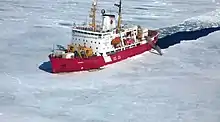 Bateau de recherche canadien en rouge et blanc traversant les glaces de l'Arctique.