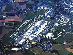 Vue aérienne de l'aéroport en juillet 2010 :• au premier plan, Le Mesnil-Amelot ;• à droite, 1re aérogare (circulaire) ;• au centre, 2e aérogare et ses terminaux.
