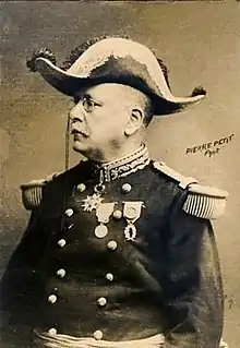 Photographie monochrome d'un homme assis, de profil, portant une tenue de général et un bicorne.