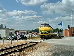 Une motrice Diesel pousse une rame réversible  à l'entrée de la gare, le long de la remise du CFV3V