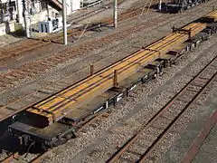 Wagons japonais à traverse mobile chargés de rails.