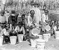 Tamisage du latex dans une plantation de l'Ouest de Java entre 1920 et 1930 par des travailleuses (dont des enfants ?) autour de leur blank officier.