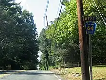 Une route bordée d'arbres et de poteaux.