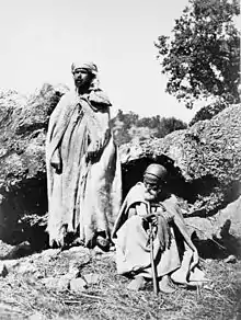 Photographie en noir et blanc montrant deux hommes, l'un debout, l'autre assis.