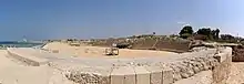 Photographie d'un amphithéâtre en ruine au bord de la mer.