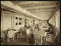 Le Café parisien du Titanic et ses fauteuils en rotin. Acajou, linoleum, staff et rotin (en partie fibres et bois coloniaux) font partie de la décoration des ponts supérieurs.