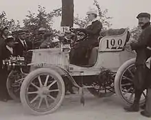 Photo d'une voiture dont l'apparence se rapproche encore d'une calèche, conduite par une femme.
