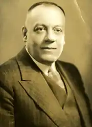 Photographie noir et blanc avec teint jaunâtre d'un homme en habit cravate.