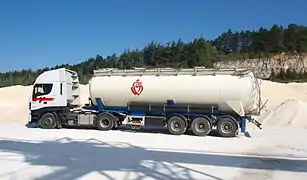 Un tracteur attelé d'une semi type citerne à pulvérulent.