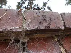 Détail d'une des briques du mur d'enceinte, provenant de la briqueterie de Gannes, comme l'indique le symbole LS.