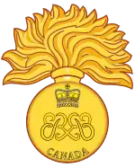 Image en couleur d'un insigne militaire composé d'une grenade allumée de 17 flammes avec deux monogrammes des lettres « ER » affrontés au centre ainsi qu'une couronne royale au-dessus et le mot « Canada » en dessous ; le tout est de couleur dorée.