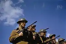 Soldats en uniforme en une rangée pointant une mitrailleuse et portant des casques
