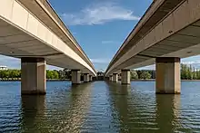 Deux grandes arcades de pont parallèles portées par plein de piliers sur une eau calme.