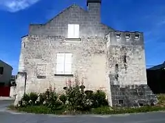 Photographie en couleurs d'un bâtiment incluant une ancienne tour carrée crénelée.