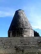Photographie en couleurs d'une petite tour terminée par un cône en pierre.