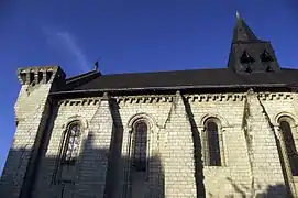Photographie en couleurs du mur d'une église avec ses modillons et des contreforts alternant avec des baies.