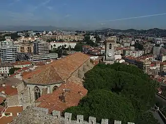 Vue sur les toits et le clocher depuis la tour de la Castre avec en arrière-plan la ville de Cannes.