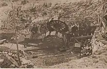 Artilleurs autour d'un canon renversé dans un vallon.